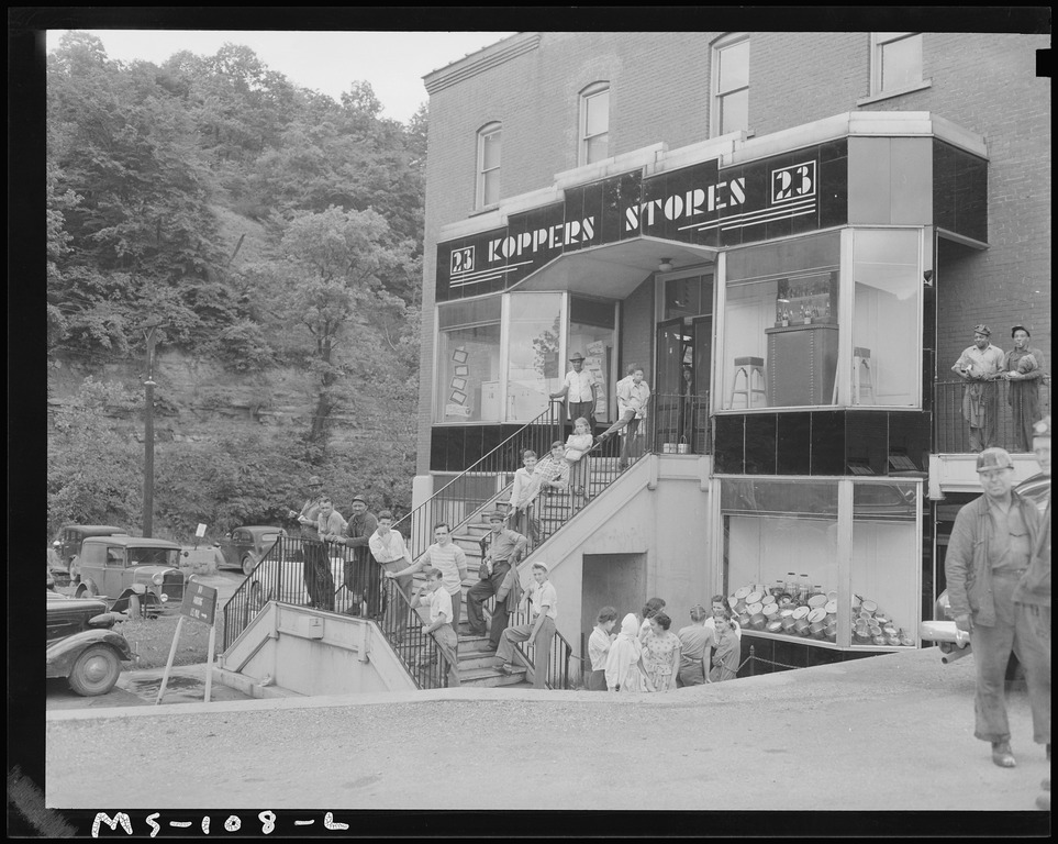 Image shows miners and their families in West Virginia standing outside of the Kopper Stores, a company store for miners.
